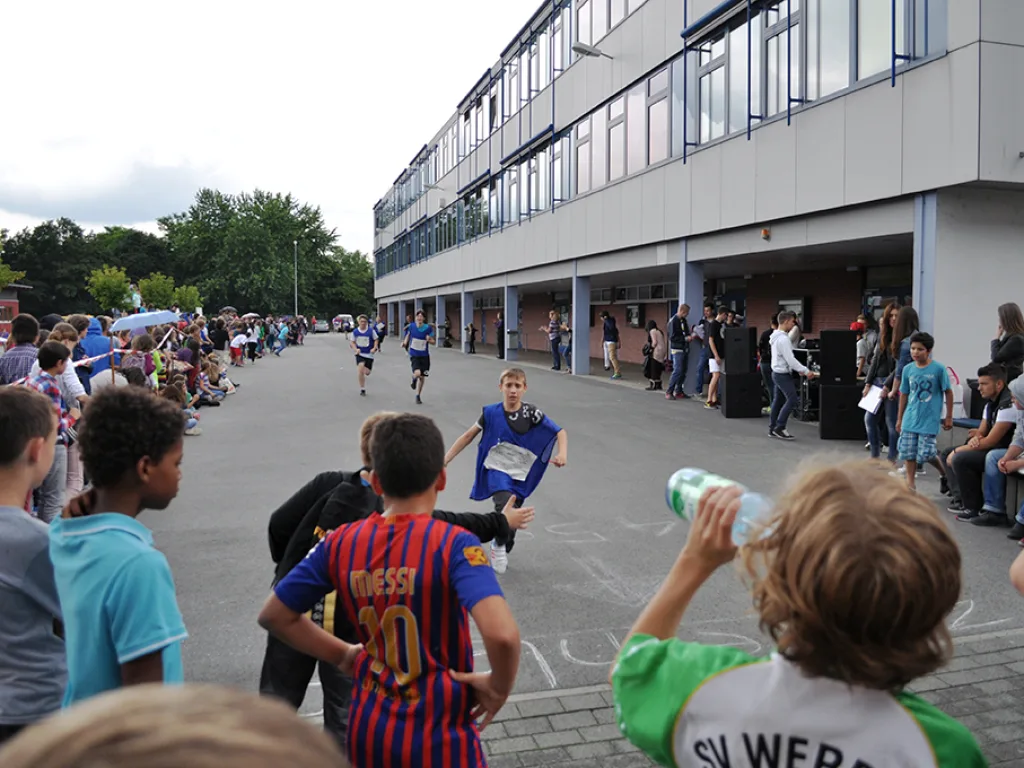 Läufer auf dem Schulhof entlang des Gebäudes.